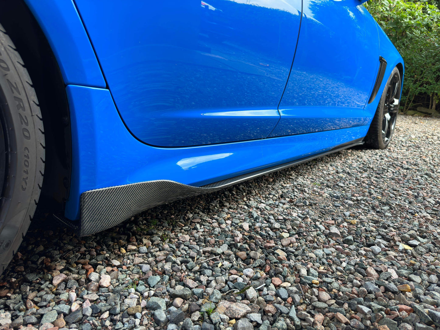 carbon fiber side skirts on a blue jaguar xf parked on a gravel road