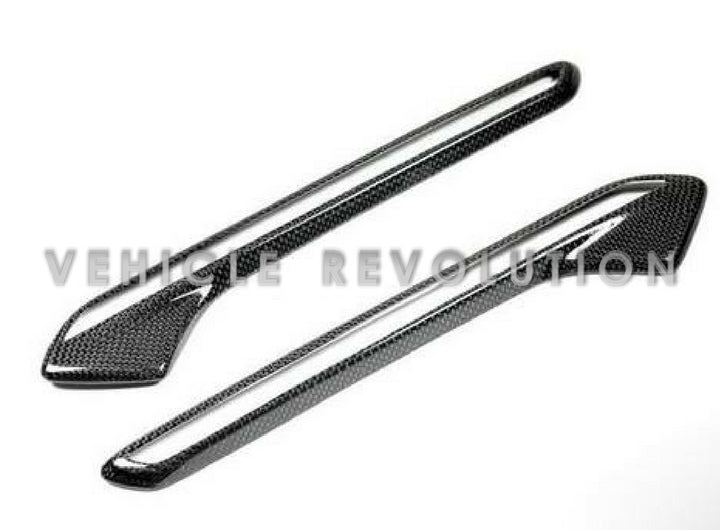 A pair of carbon fiber and ABS fender light trims for BMW vehicles, featuring a gloss black finish and a textured weave design.