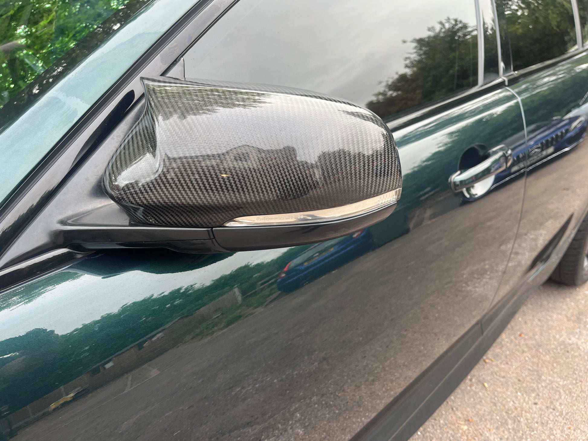 Carbon fiber car mirror on a vehicle with a blurred background