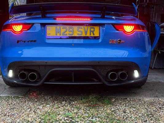 Blue Jaguar F-Type car with visible license plate 'M29 SVR' on a gravel surface.