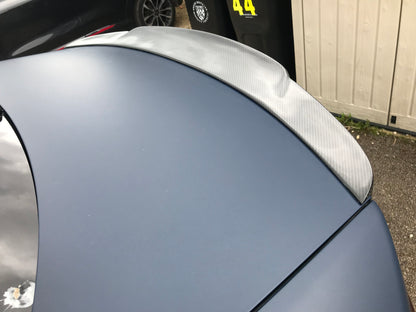 blue jaguar xe trunk boot spoiler carbon fibre close up on a blue jaguar xe in a parking spot residence with a shed behind