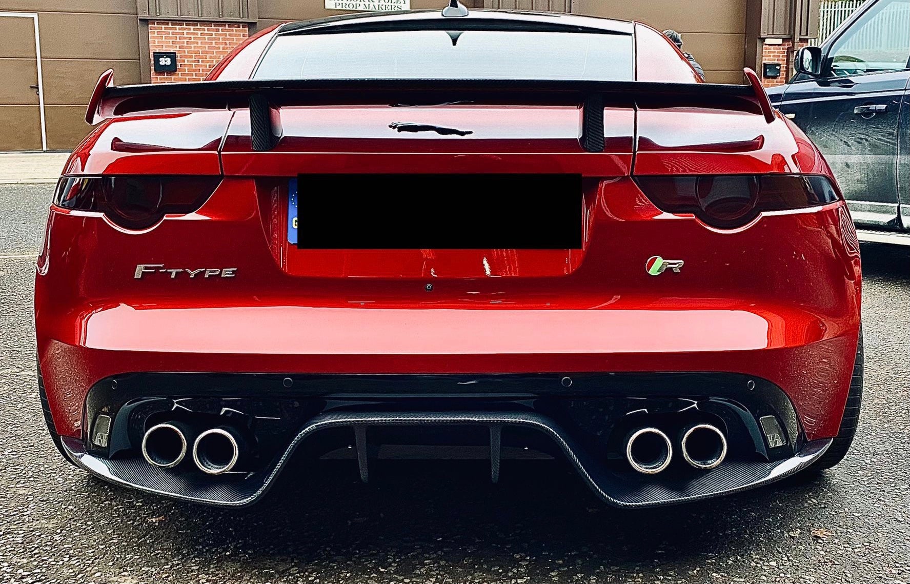 The image shows a red Jaguar F Type V8 with the carbon fibre diffuser installed at the rear of the vehicle.