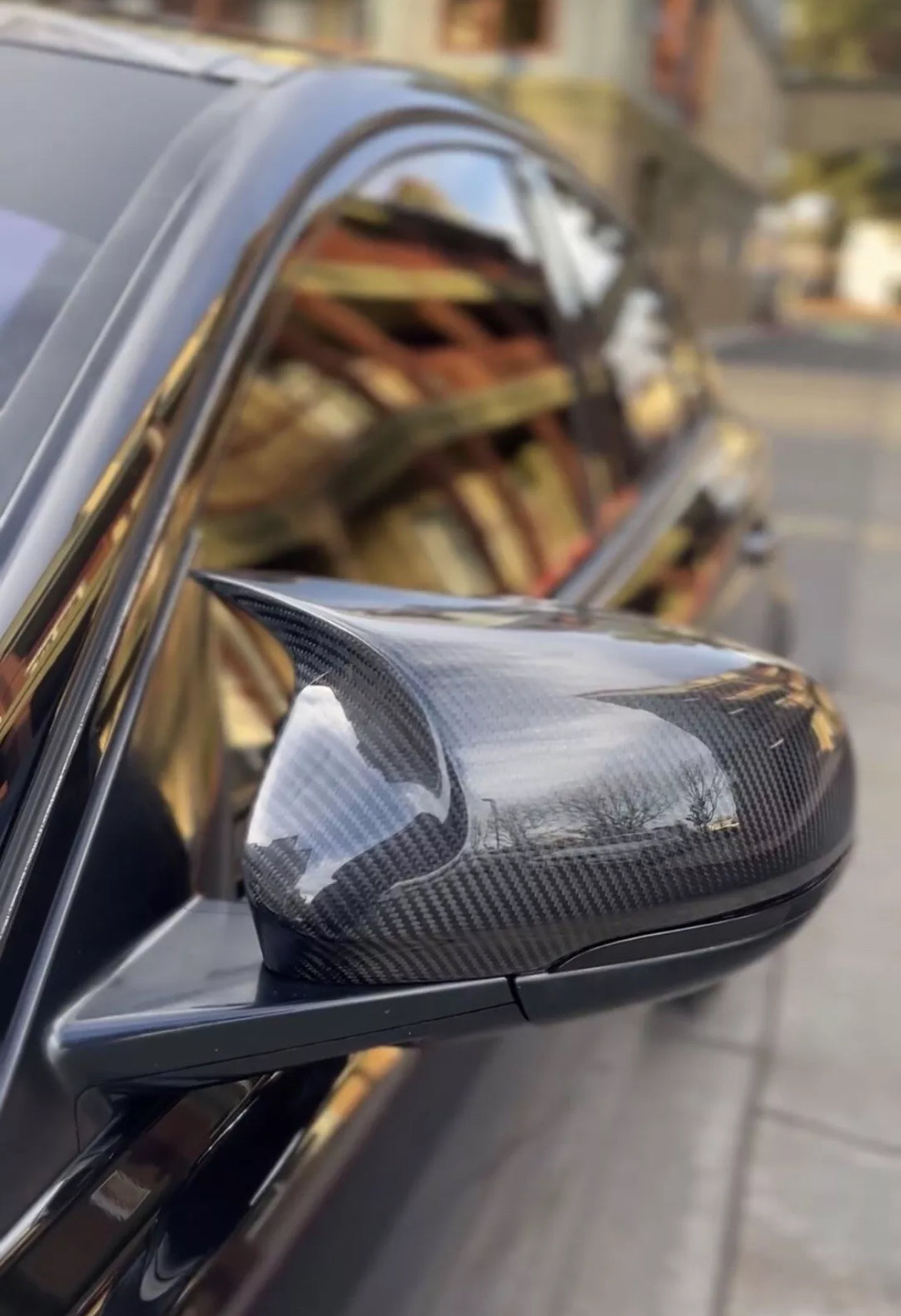 Carbon fiber car mirror on a vehicle with blurred background