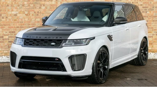 A white Range Rover Sport with a carbon fibre body kit, featuring blacked-out grille and tailgate trim covers, side vents with SVR design, and mirror covers.